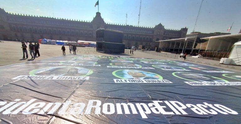 Activistas despliegan lona en el zócalo, con imágenes de “narco-gobernantes”