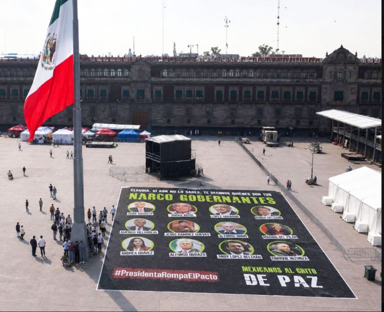 Activistas despliegan lona en el zócalo, con imágenes de “narco-gobernantes”